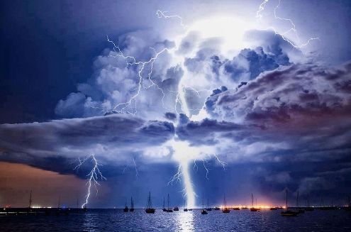 Корабли, плывущие по воде, освещены вспышками молний